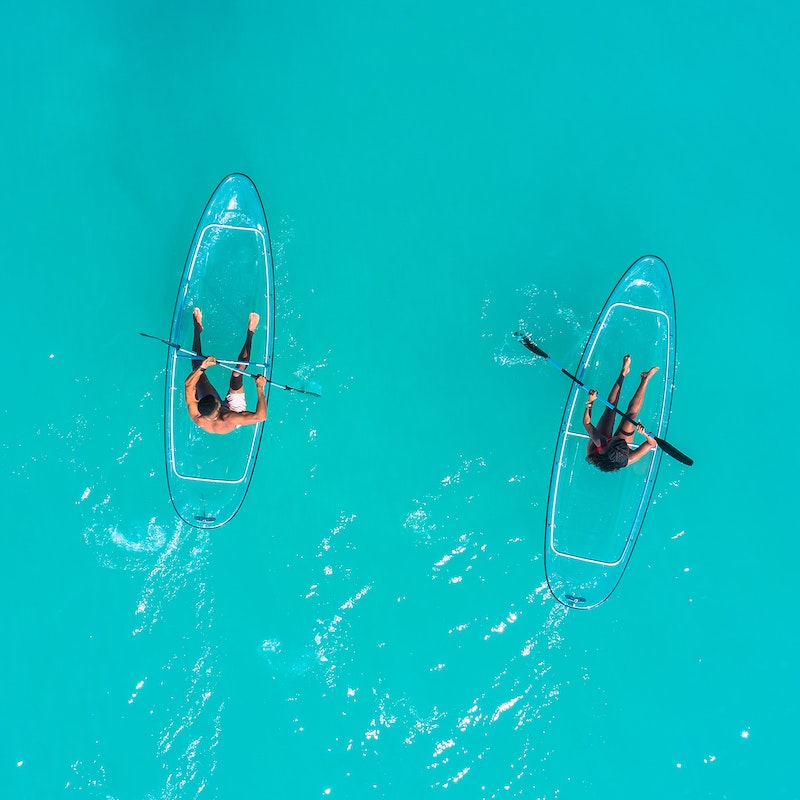 pareja remando sobre kayaks transparentes en aguas turquesas
