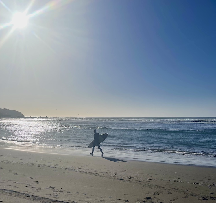 Surfista caminando en la playa con su tabla en Pichilemu
