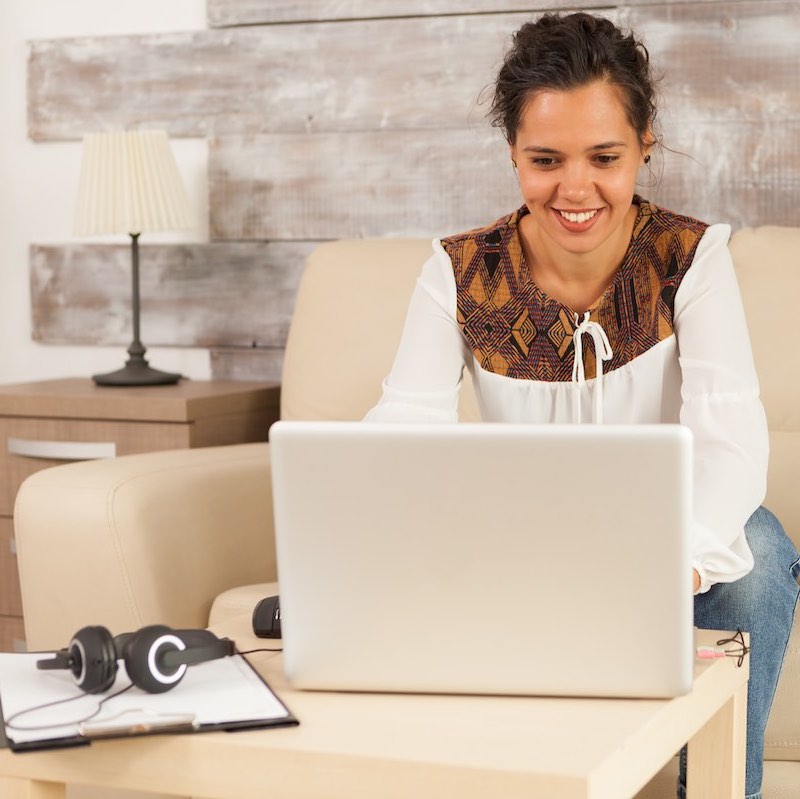 Mujer frente a computadora con block de notas y audífonos a un lado
