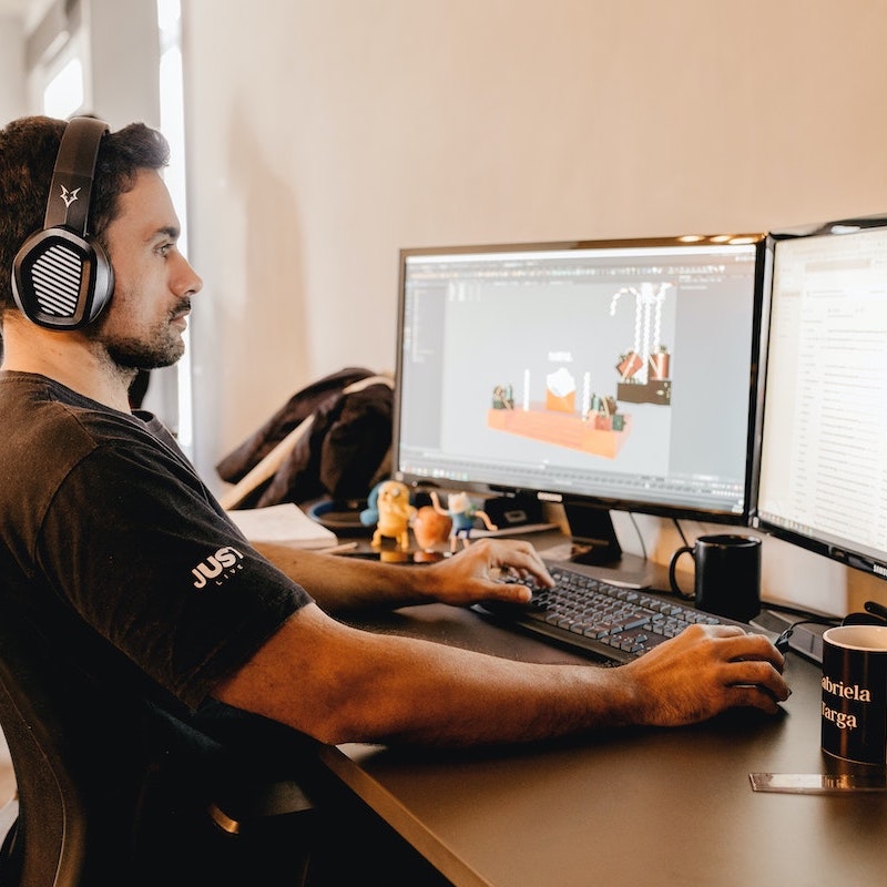 Hombre trabajando frente las pantallas mientras escucha música para trabajar