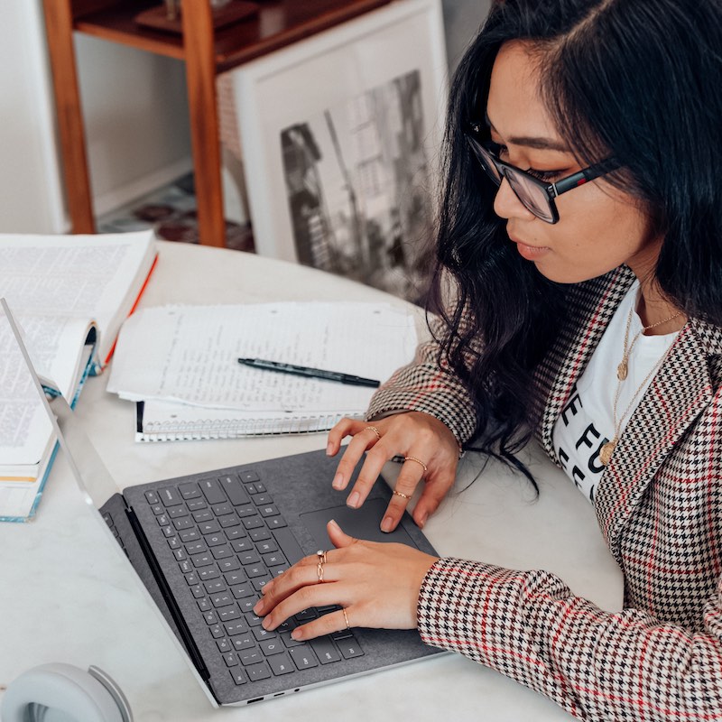 mujer con lentes trabajando en su computadora portátil  