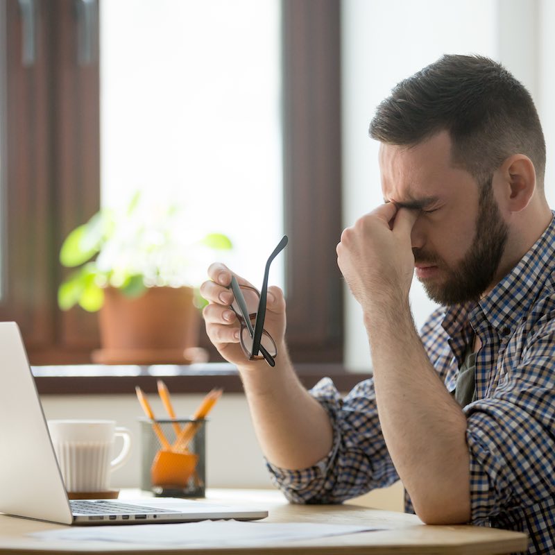 Hombre frustrado frente a computadora. Conseguir trabajo online no es tan fácil como parece.