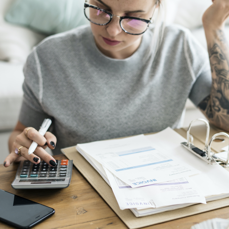 mujer usando calculadora y viendo facturas en la mesa