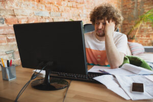 hombre frente a computador frustrado por estafas comunes online