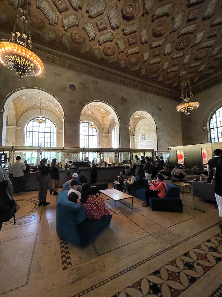 Vista del techo, las lámparas, las columnas y las personas que ocupan el edificio histórico que ahora se conoce como el espacio de coworking más bonito del mundo