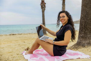 La asistente virtual Giulia Chilin con su computadora en una playa