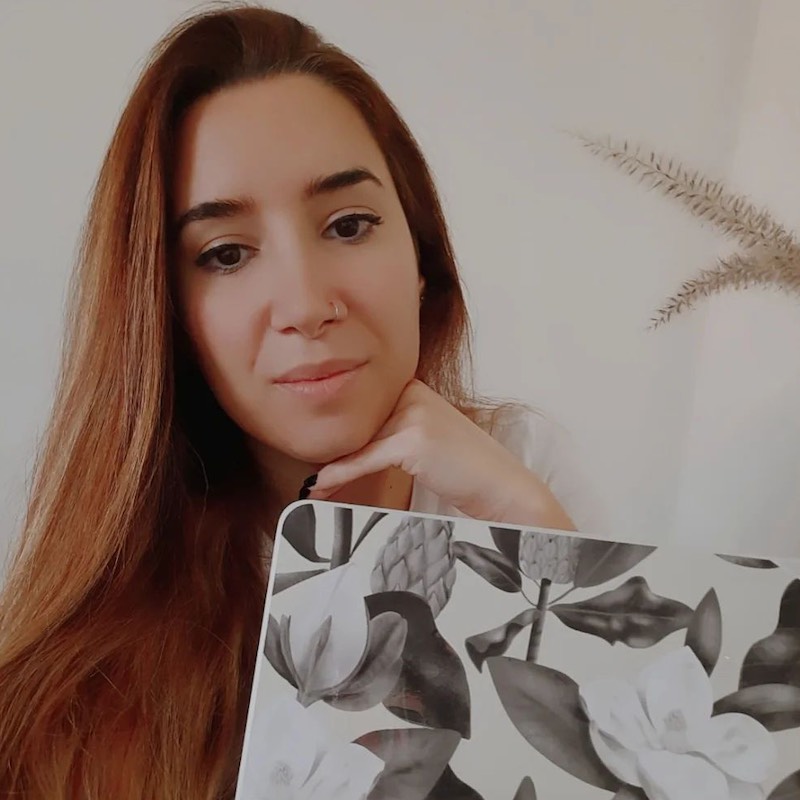 Fotografía de perfil de Anis una freelancer en el que se aprecia su rostro y su computadora con un protector diseñado por ella.